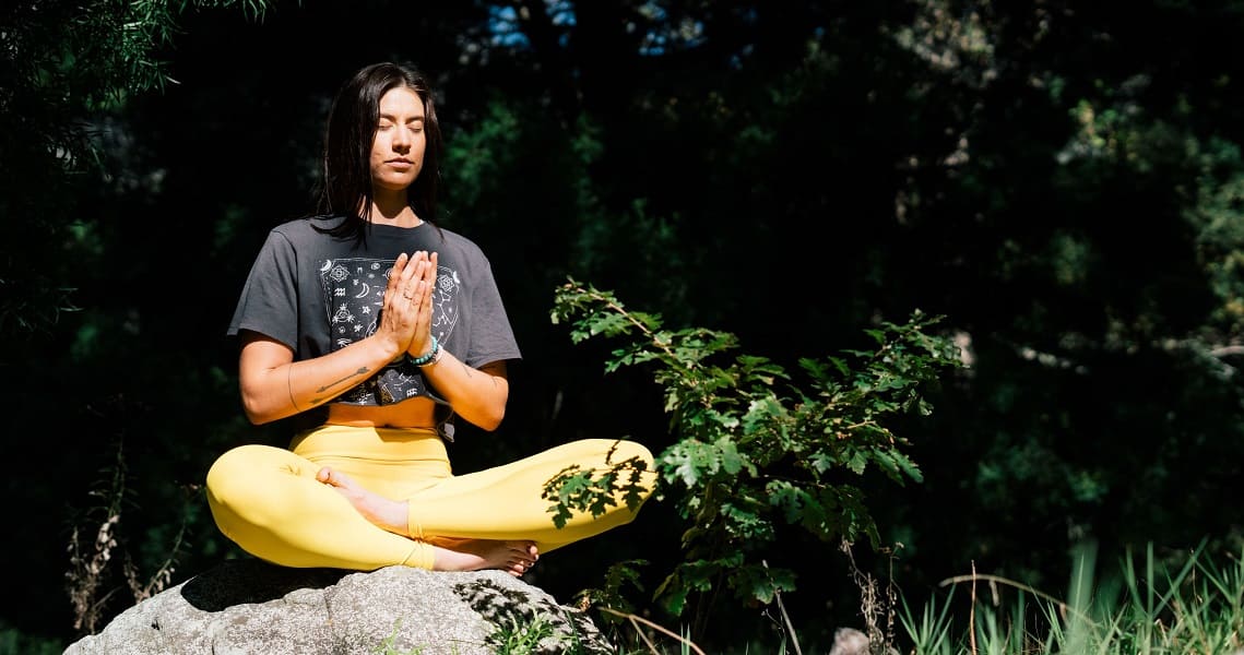Frau macht Achtsamkeitsübung und meditiert im Freien
