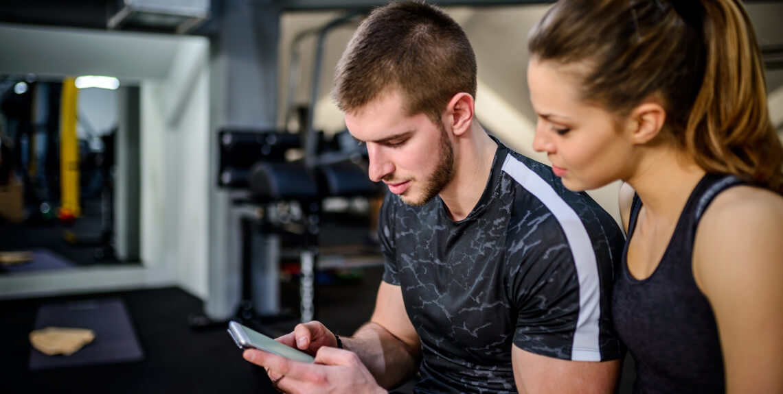 Trainer schaut mit Klientin auf Handy 
